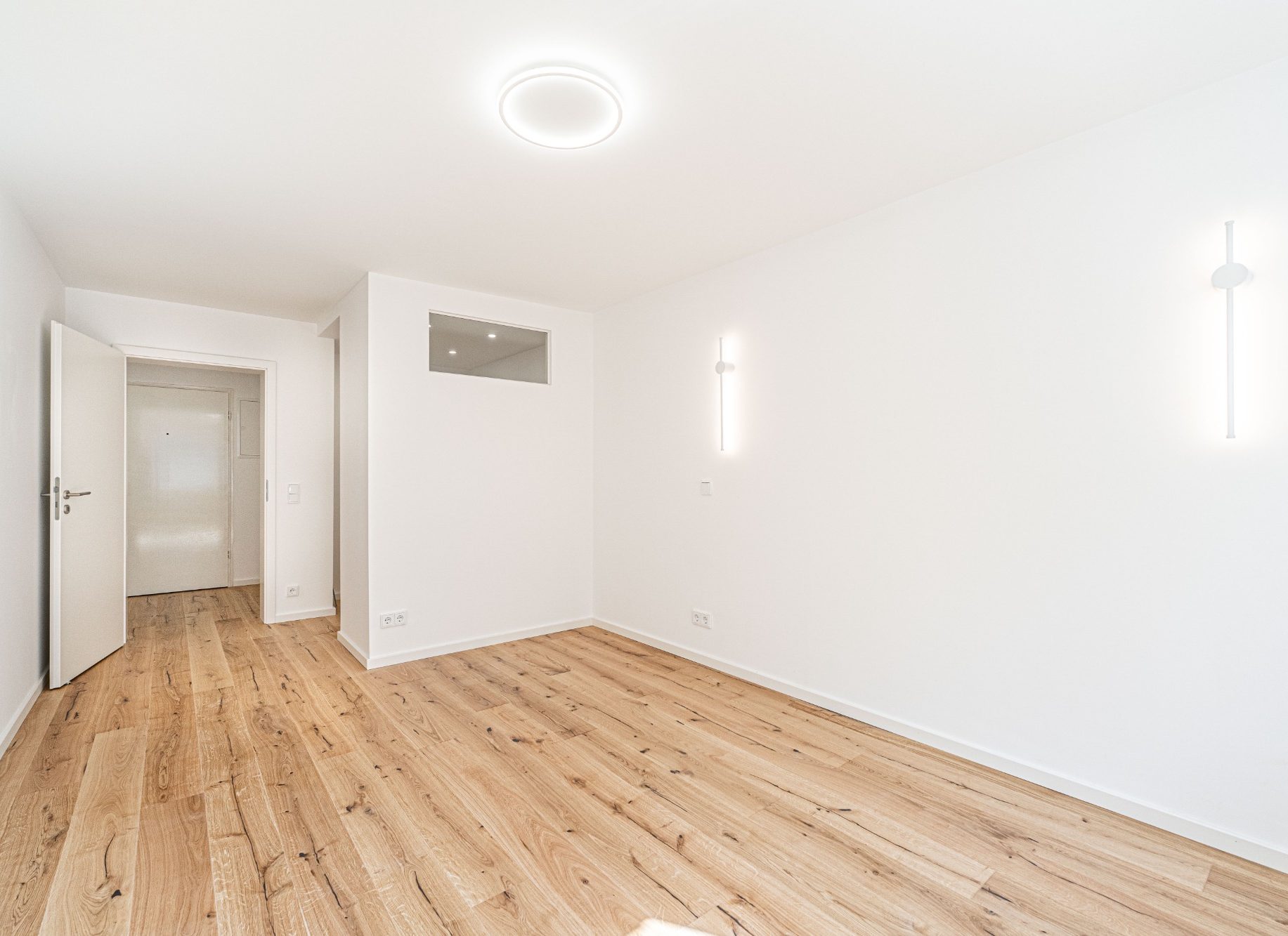 Wohnungssanierung in München mit modernem Wohnraum, weißen Wänden und integrierter Beleuchtung