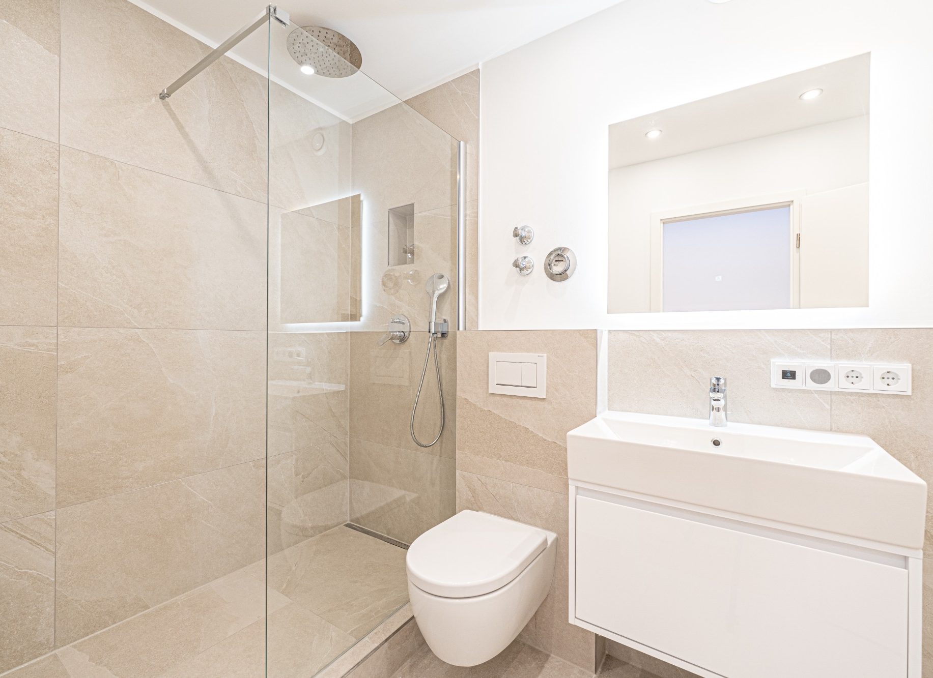 Badsanierung in München modernes Badezimmer mit Walk-in-Dusche, beigen großformatigen Fliesen und integrierter Nische