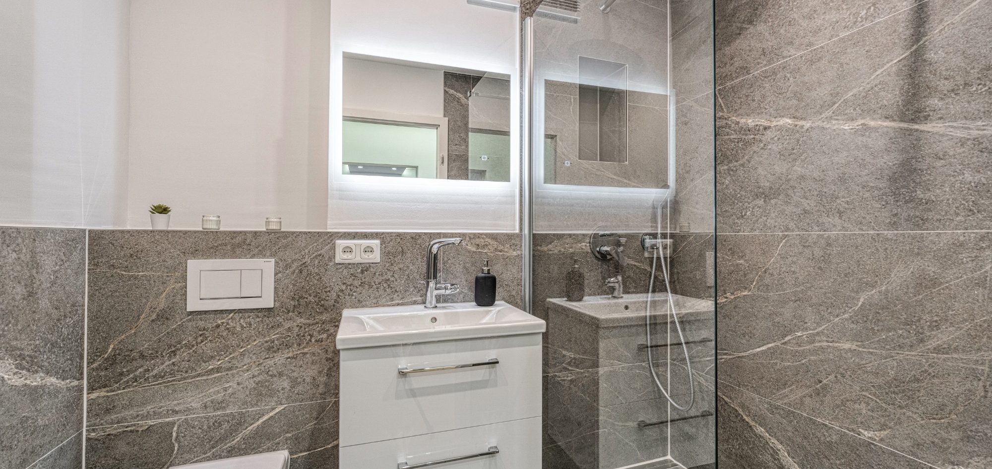 Badsanierung München hochwertiges Badezimmer mit großformatigen Fliesen, Walk-in-Dusche und integriertem Spiegel